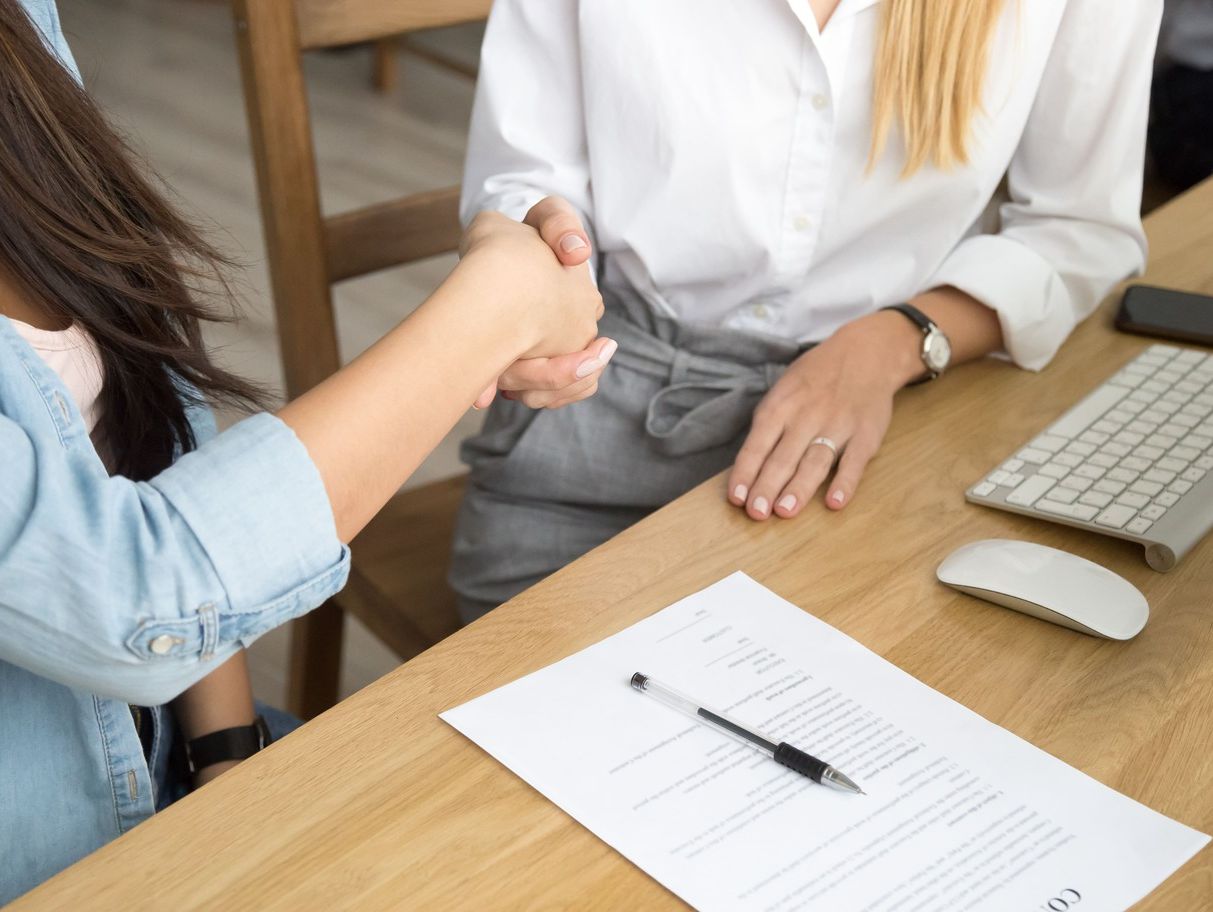 mujeres dándose la mano sentadas en escritorio